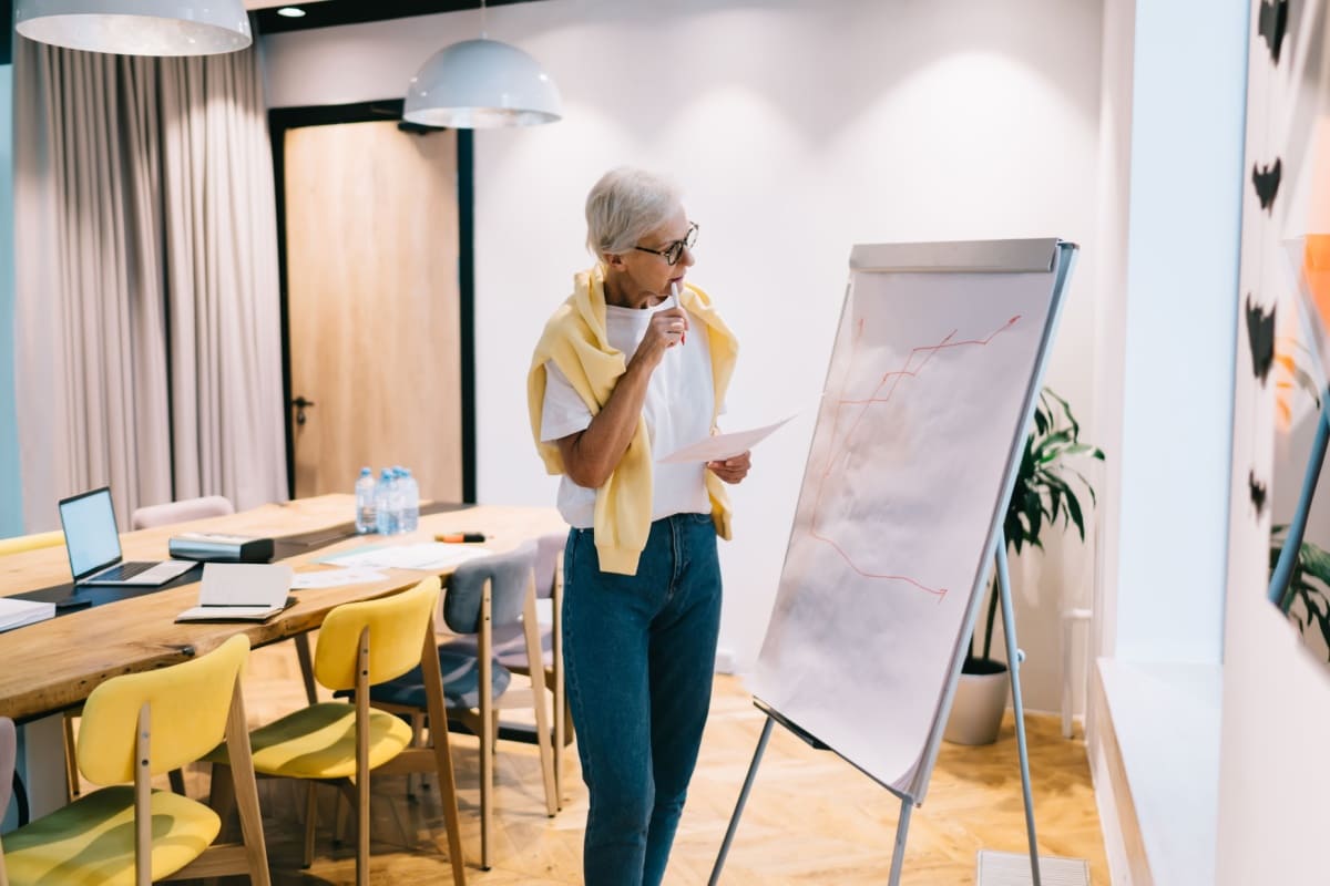 femeie privește axe pe un flipchart fix într-o sală de ședințe