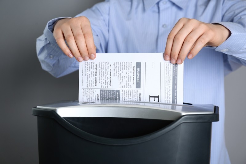 barbat care introduce un document in distrugatorul pentru documente barbat care introduce un document in distrugatorul pentru documente